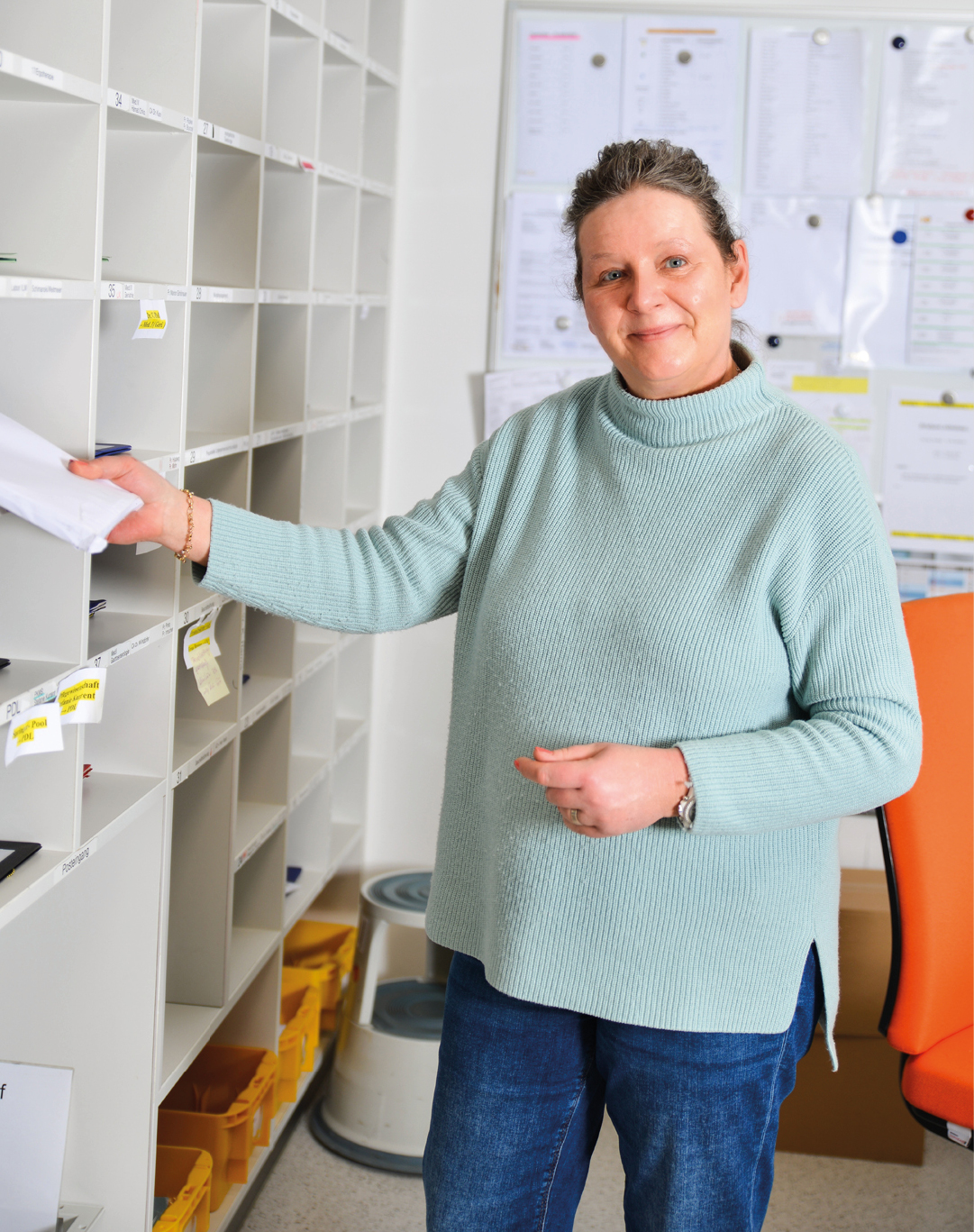 Mitarbeiterin in der Postelle, die gerade Post einsortiert.