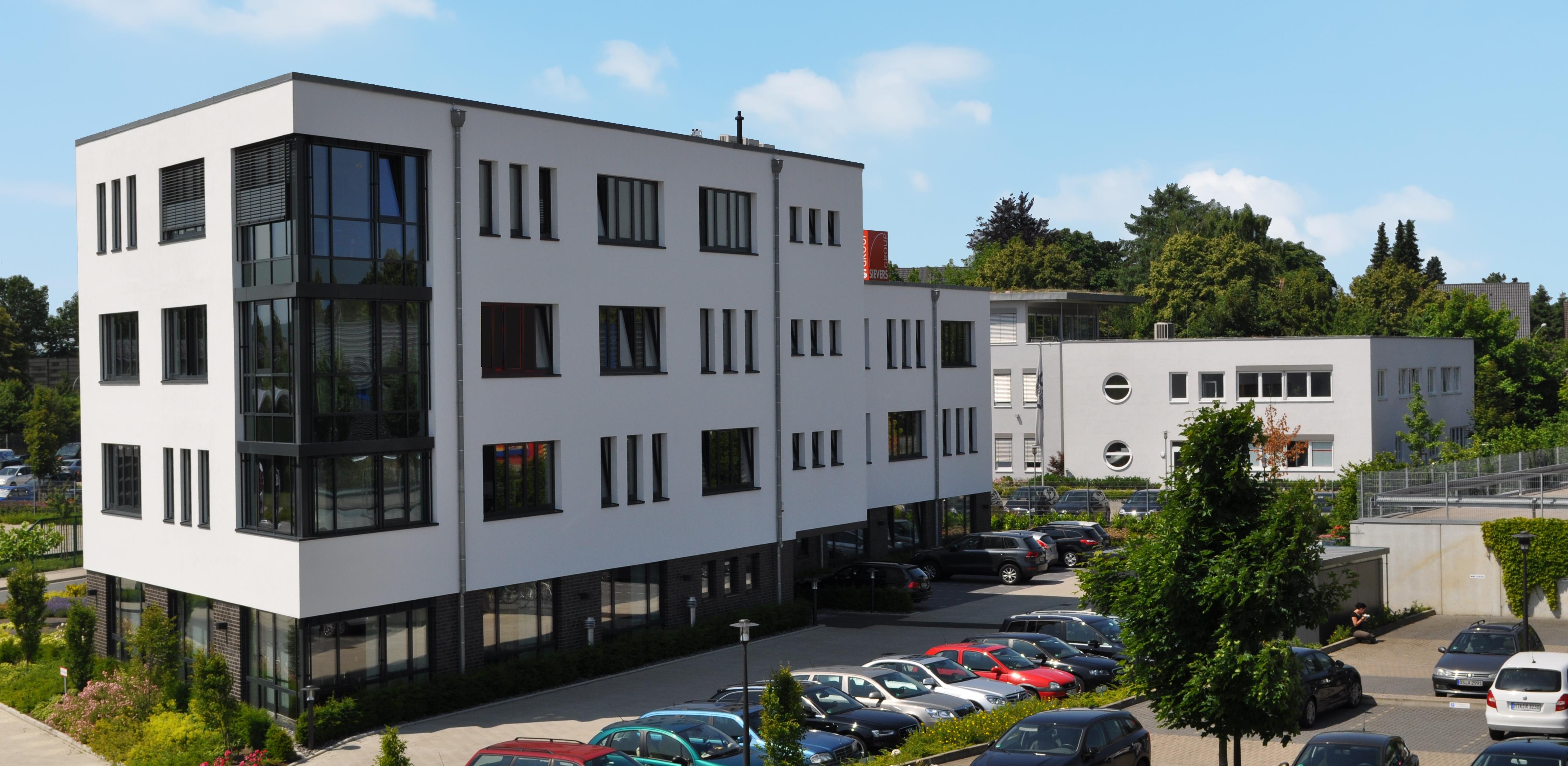 Mitarbeiter der SIEVERS-GROUP vor dem Event-Center mit dem roten leuchtenden SIEVERS-Würfel