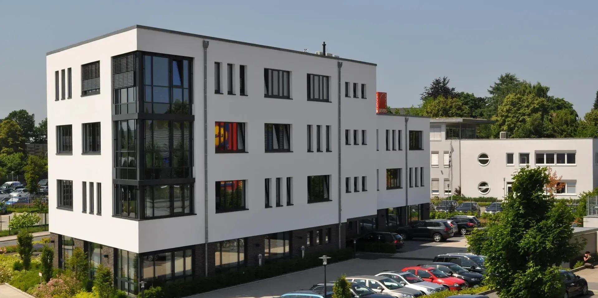 Mitarbeiter der SIEVERS-GROUP vor dem Event-Center mit dem roten leuchtenden SIEVERS-Würfel