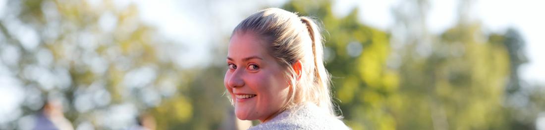 Junge Frau lächelt freundlich in die Kamera.