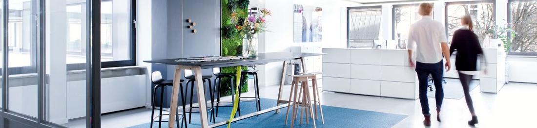 Zwei Menschen laufen durch den Empfangsbereich eines modern designten Büros