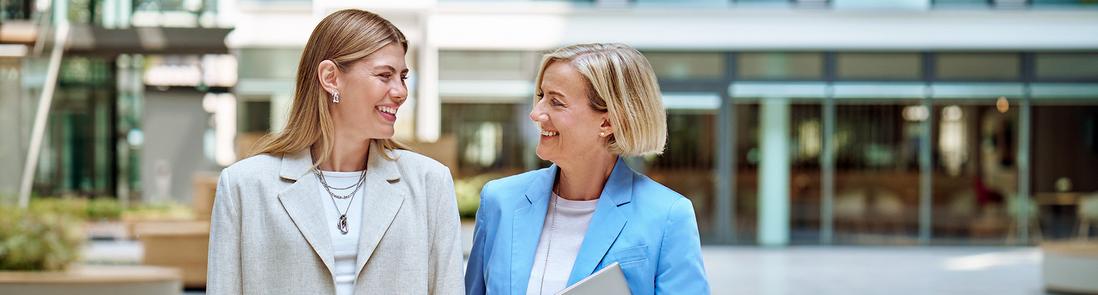 Zwei Frauen, die sich unterhalten, lachen und auf die Kamera zu laufen.
